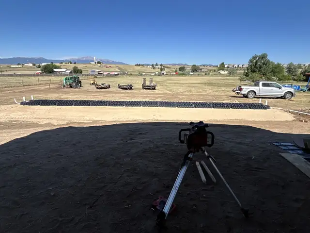 Drain field chambers laid out in a line with a surveying transit in the foreground