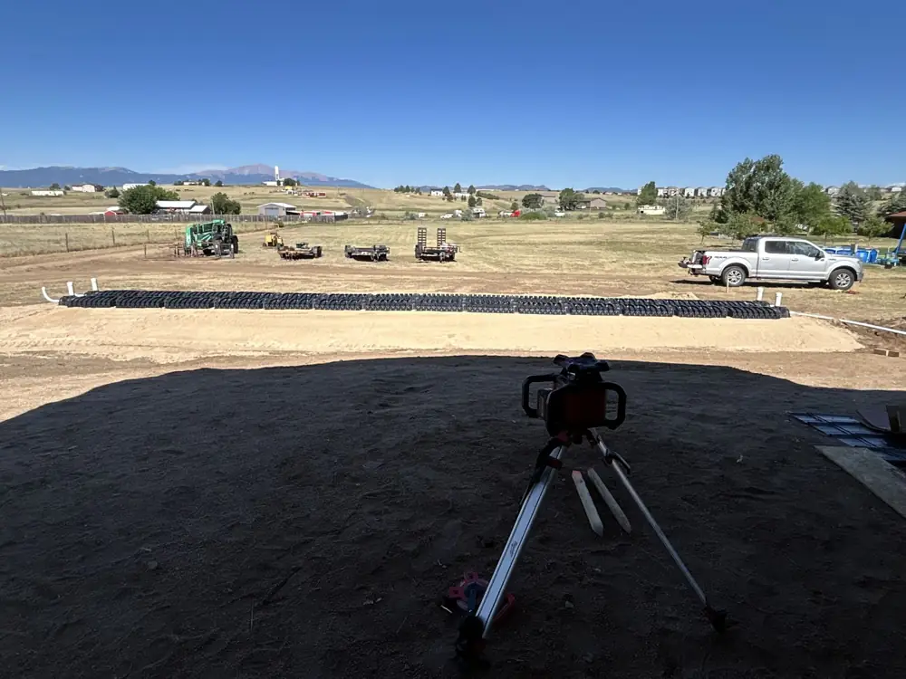 Drain field chambers laid out in a line with a surveying transit in the foreground