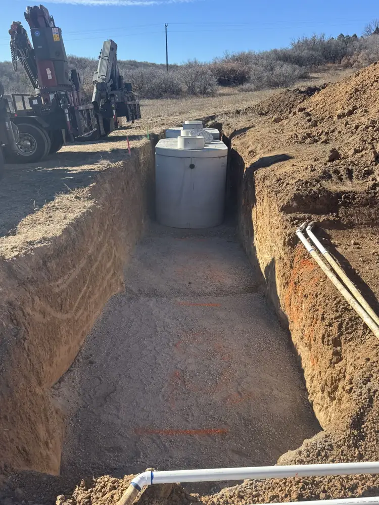 Septic tank set in an open trench with a crane truck in the background