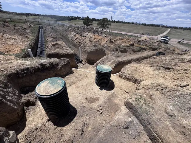 Septic tanks and drain field trenches excavated across an open property