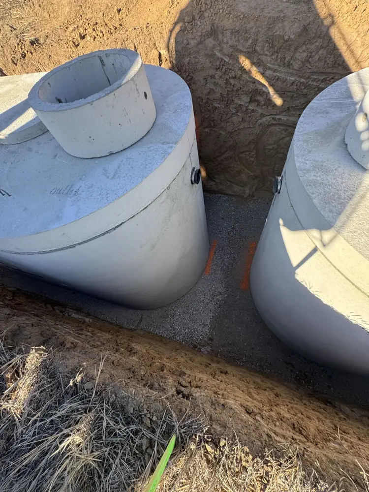 Two concrete septic tanks set in a trench side by side